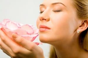 Woman holding flower and smelling pleasant scent. 