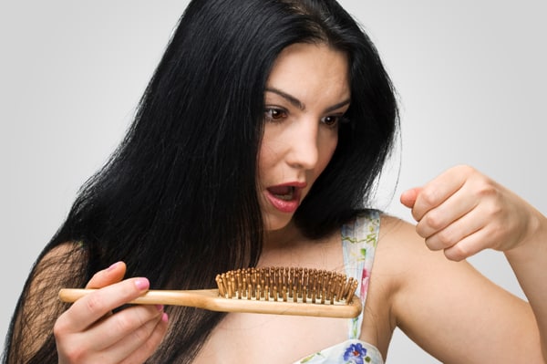 Woman pulling hair out of her brush,