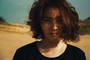 Woman with short hair smirking is desert.