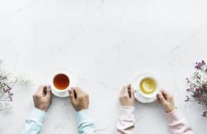 Birds eye view of hands holding tea cups filled with tea.
