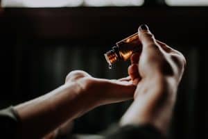 Woman hands dripping oil out of glass bottle. 