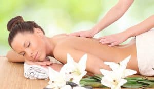 Woman getting a massage surrounded by white flowers.