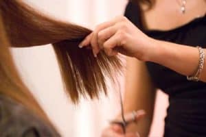 Hair about to be cut by scissors.