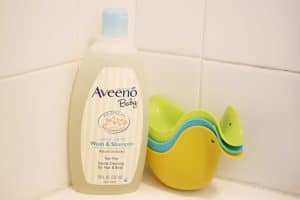 Aveeno baby wash on side of bathtub.