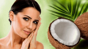 Woman with hands on face next to an open coconut. 