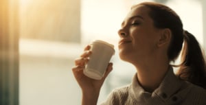 Woman closign her eyes and holding a cup.