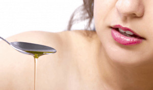 Woman holding spoon with oil dripping from it.