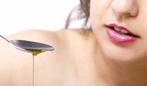 Woman holding spoon with oil dripping from it. 