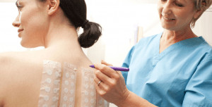 Woman getting a patch test on her back by doctor.