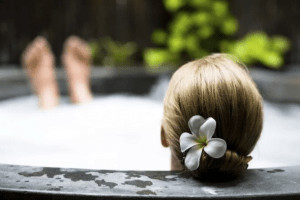 Woman with back of head to camera in an outdoor bubble bath. 