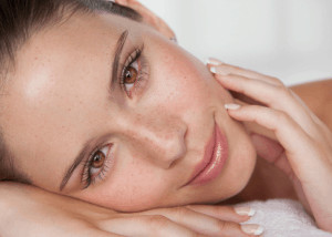 Woman lying with head tilted and hand on cheek. 