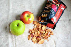 Open packet of Bare Snacks Apple Chips next to two apples. 