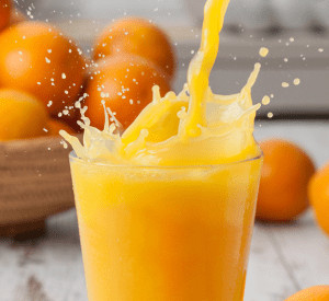 Orange juice being poured into glass with oranges in background. 