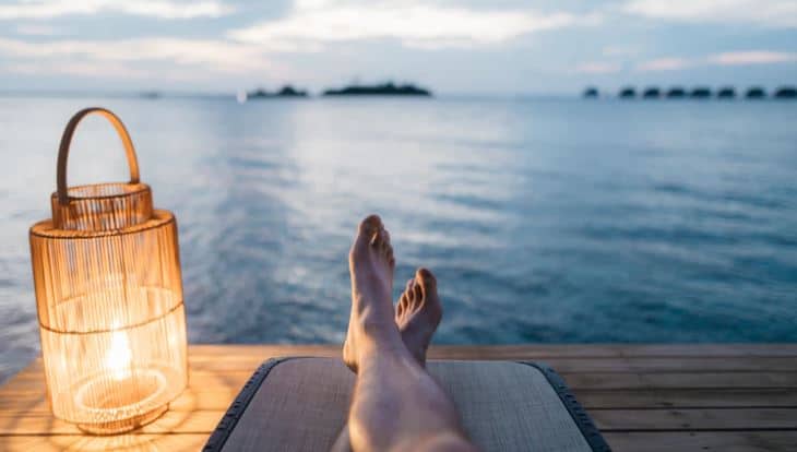 Person relaxing by a lake with feet up.