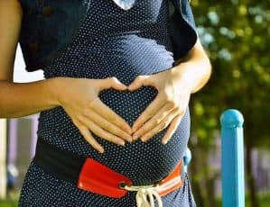 Pregnant woman using hands to make a heart on her stomach. 