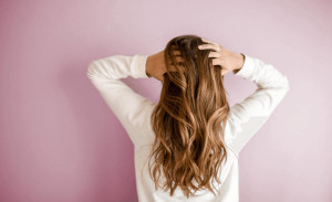 Back of woman running fingers through the back of her hair. 