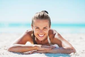 Blonde woman smiling on beach.