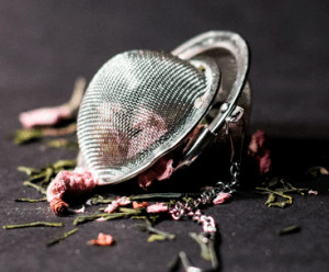 Tea infuser surrounded by herbs. 