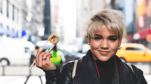 Woman holding a piece of sushi. 