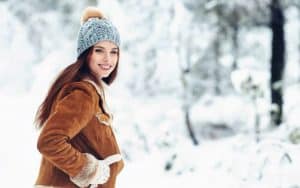 Woman smiling outdoors in winter clothes surrounded by snow.