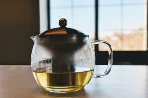 Tea pot on table in front of window.