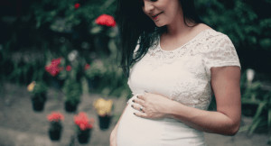 Woman holding pregnant stomach and smiling. 