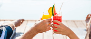 Two hands holding tropical drinks. 