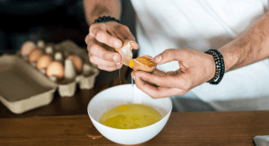 Man breaking an egg over a bowl. 