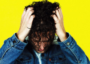 Man holding his head in his hands on yellow background. 