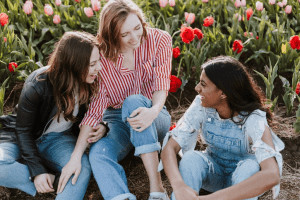 Three friends talking in field of flowers.