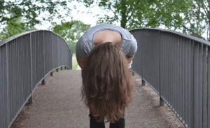 Woman standing on a bridge with her head flipped upside down. 