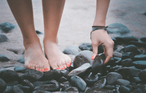 Close up of feet on pebbled beach.