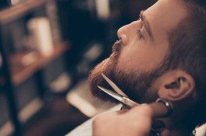 Side view of man having beard trimmed.