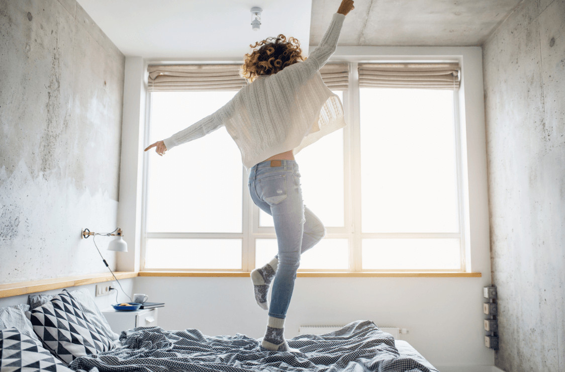 Woman with energy dancing on bed.