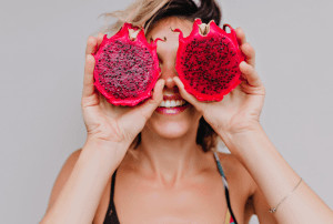 Woman smiling with dragon fruit on her eyes.