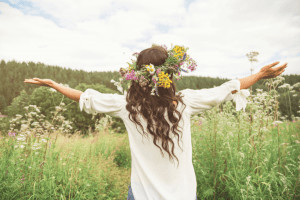 Back view of woman in field with flower crown in her hair.