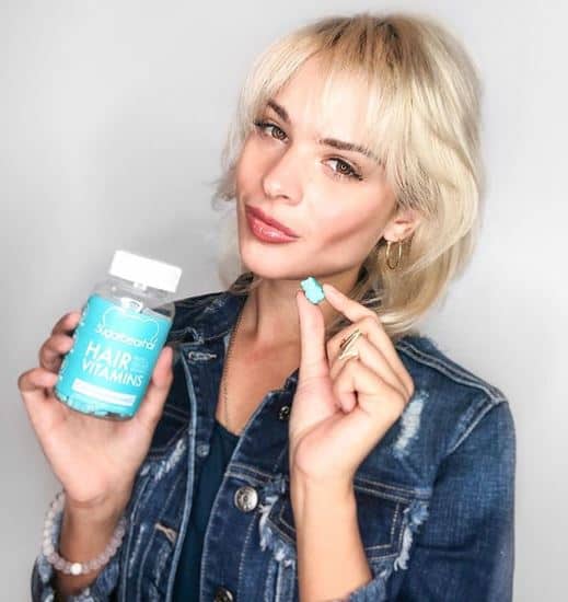 Woman holding bottle of SugarBearHair Vitamins.