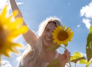 Girl holding sunflower to face.