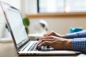 Side view of hands typing on laptop. 