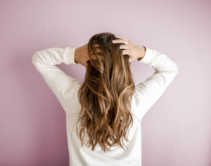 Woman running hands through hair on pink background.