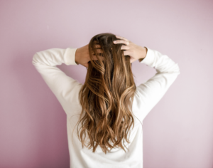 Woman running hands through hair on pink background. 