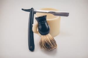 Single blade razor balancing on mug and broad brush.