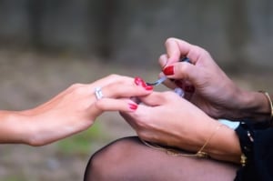 Red nail polish being painted on nails.